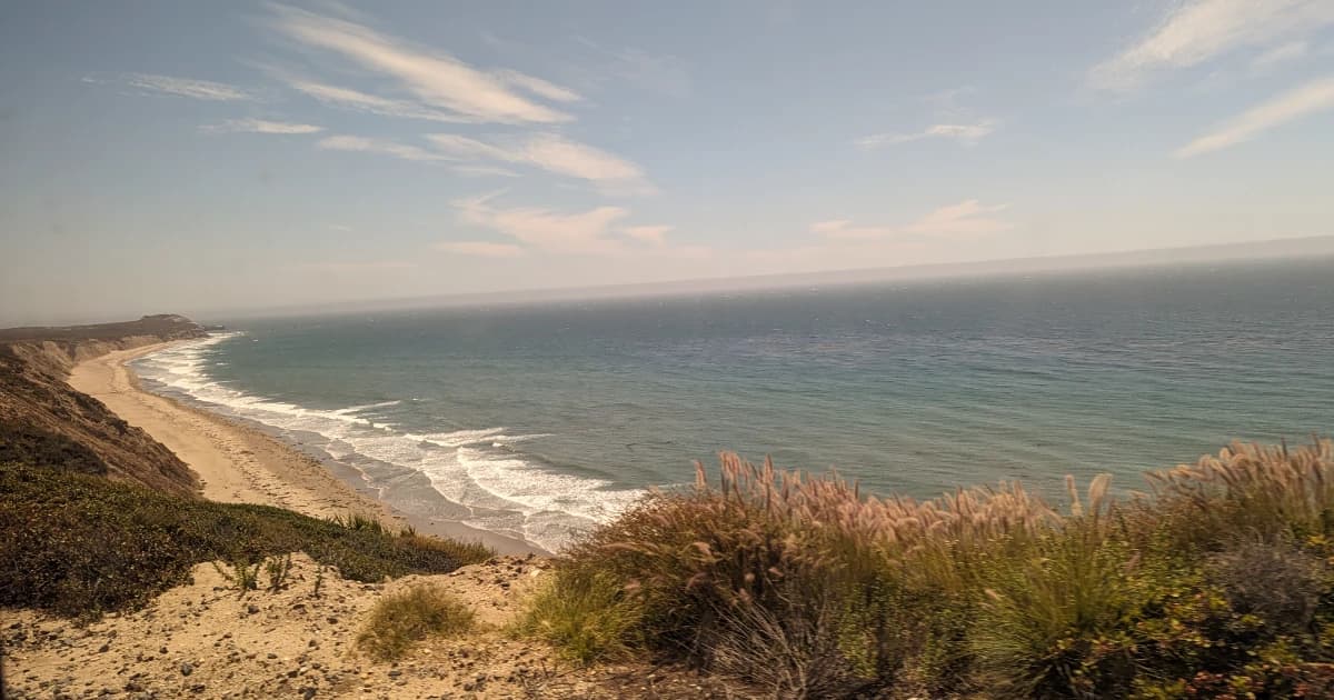 Pacific Ocean, sandy beach and low rise cliffs viewed from the Coast Starlight